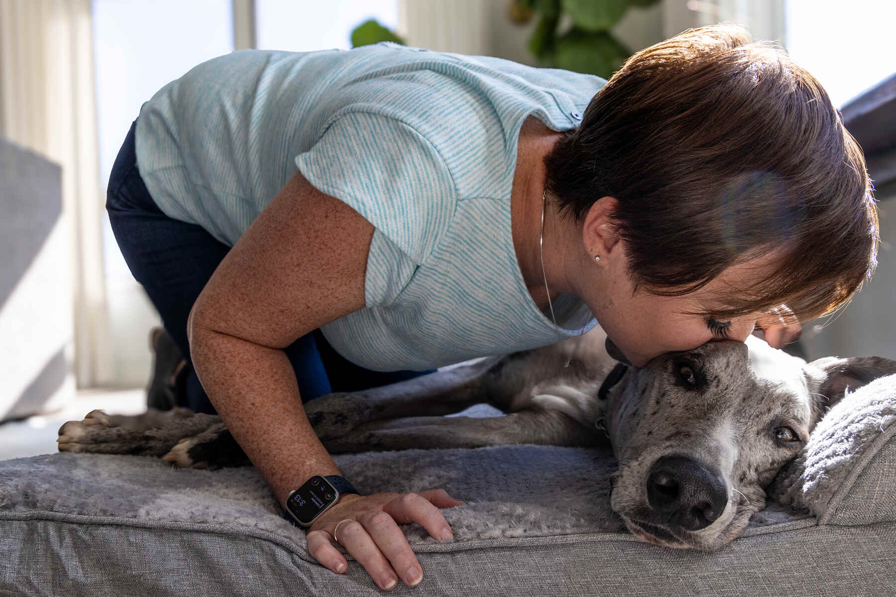 A woman affectionately kisses a dog on the head