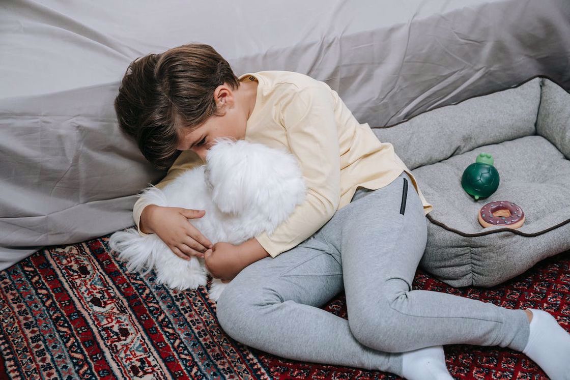 Little boy cuddling his white puppy