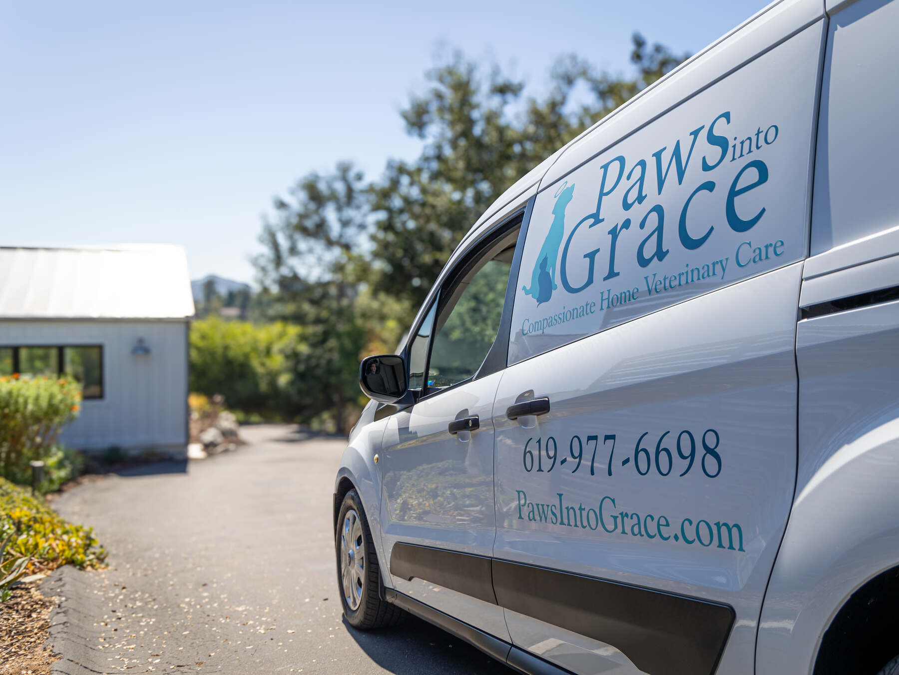 A white veterinary care van parked outside a home