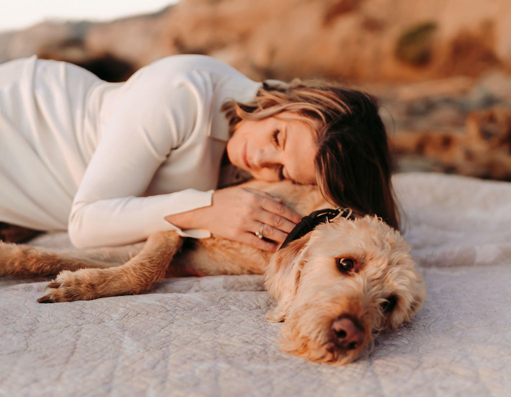 Dr. Elizabeth Benson resting her head on a doodle lying on a blanket, eyes closed