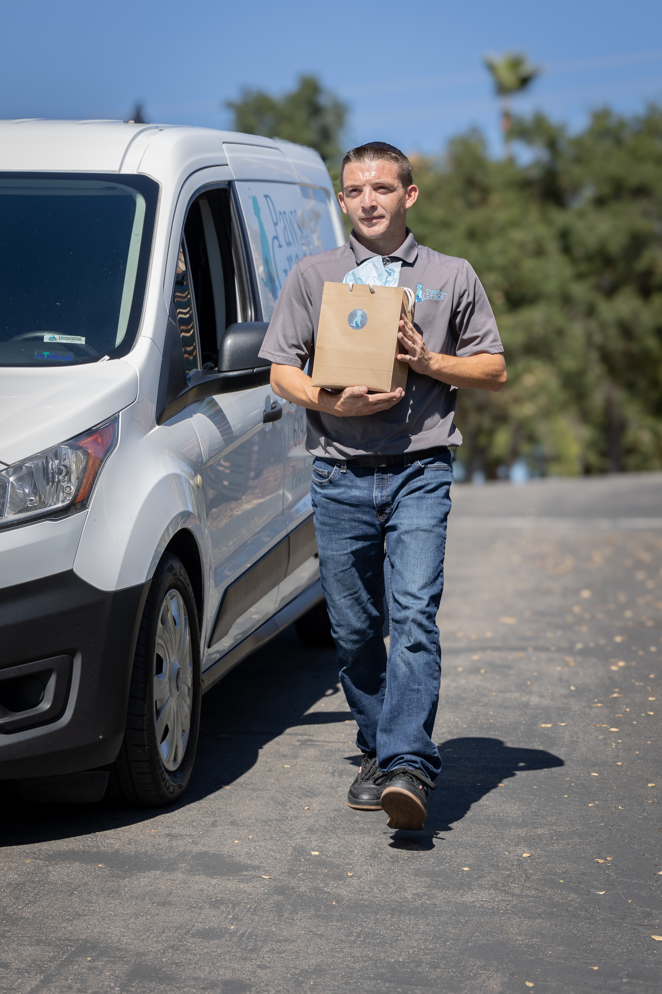A man stands in front of a van, holding a box with both hands