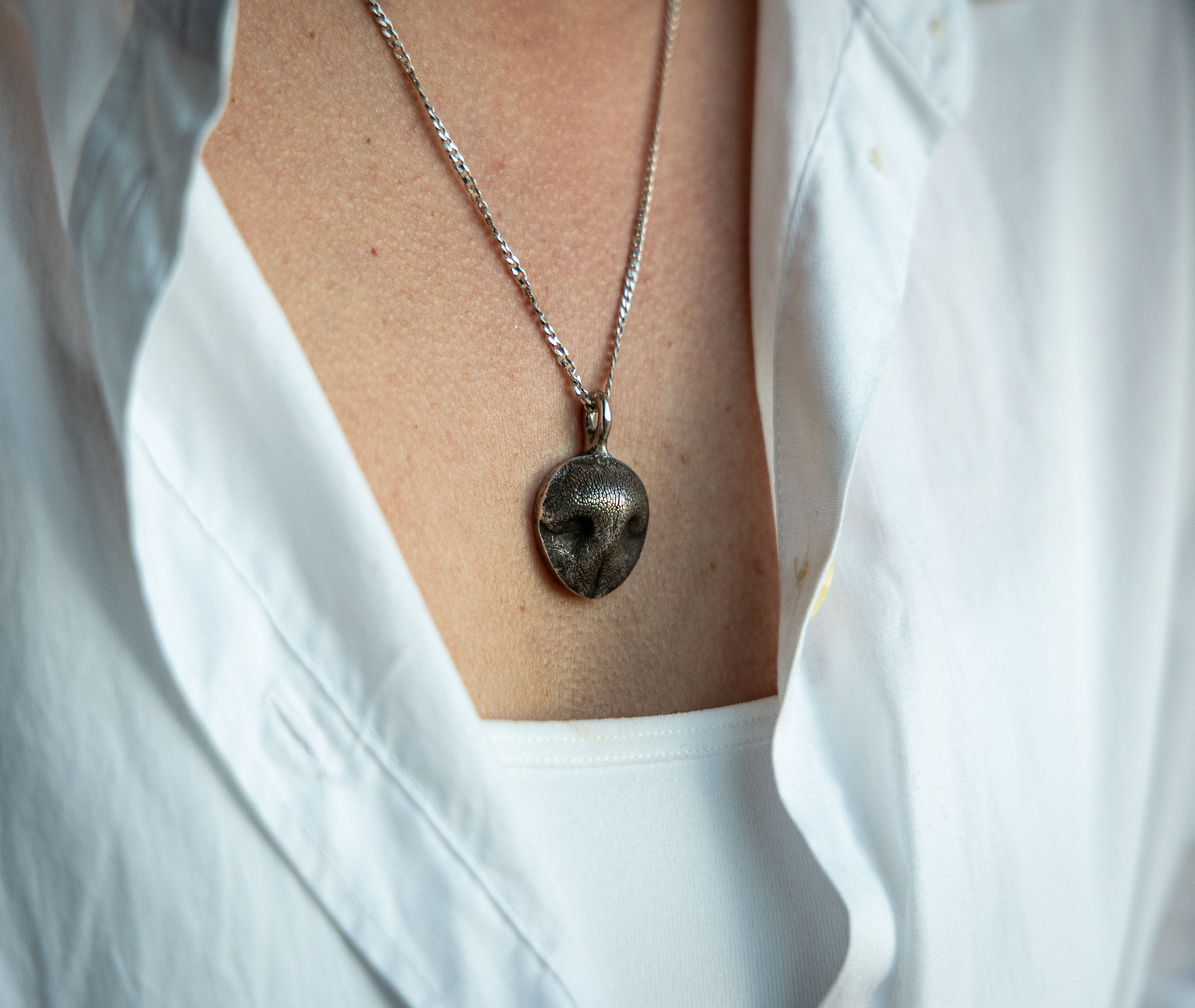 Close-up of a necklace with a pendant shaped like a pet’s nose