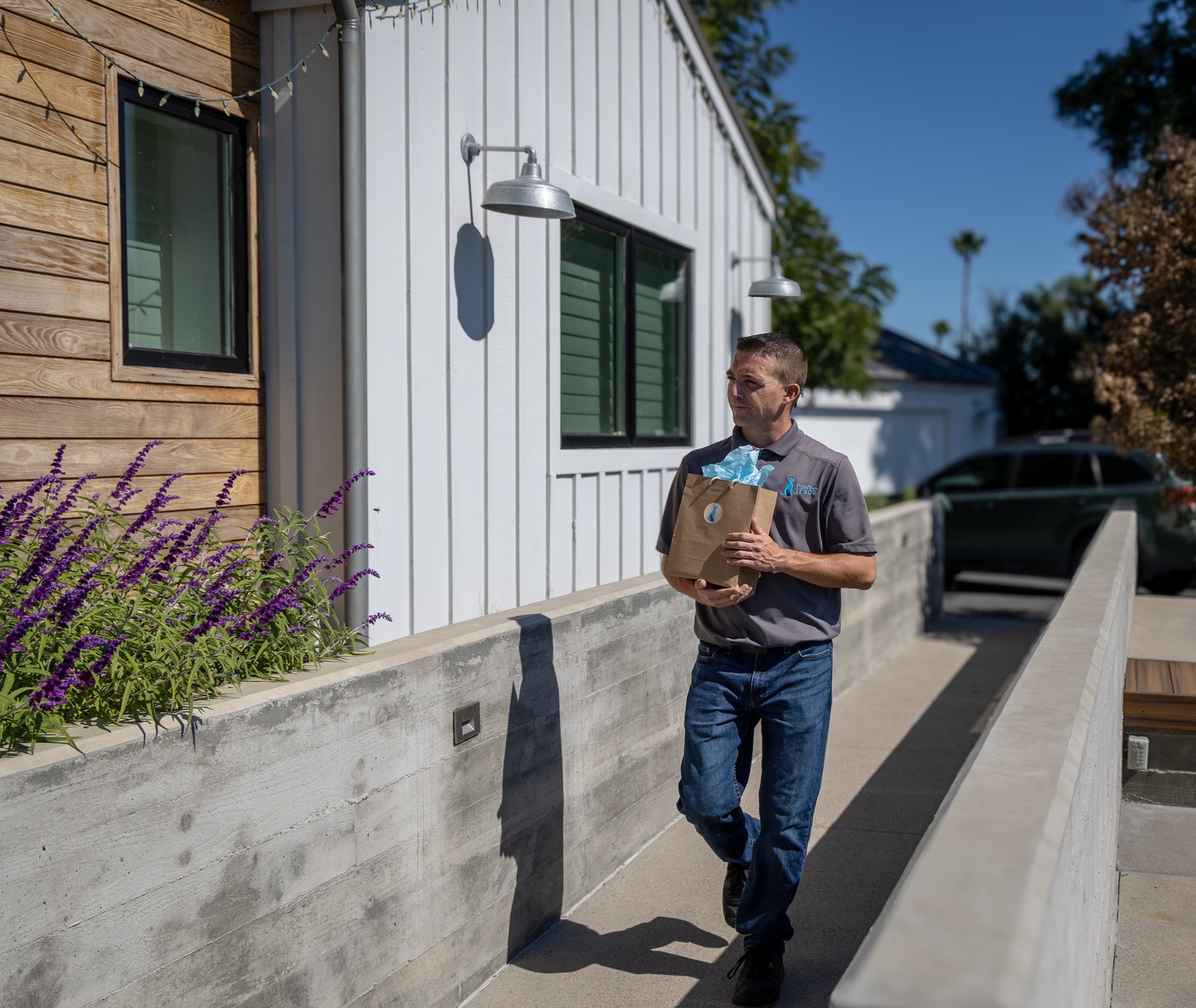 Man carrying a paper bag while walking outside a house