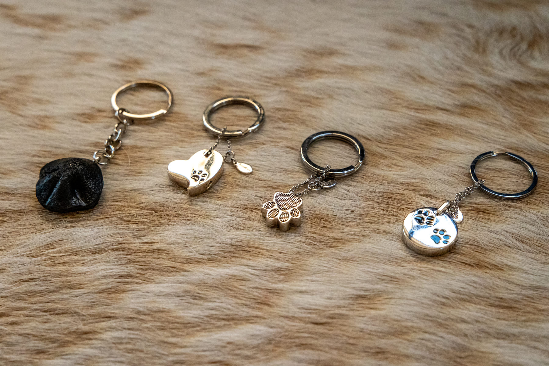 Four keychains with clippings and keepsakes laid on a brown fur fabric.