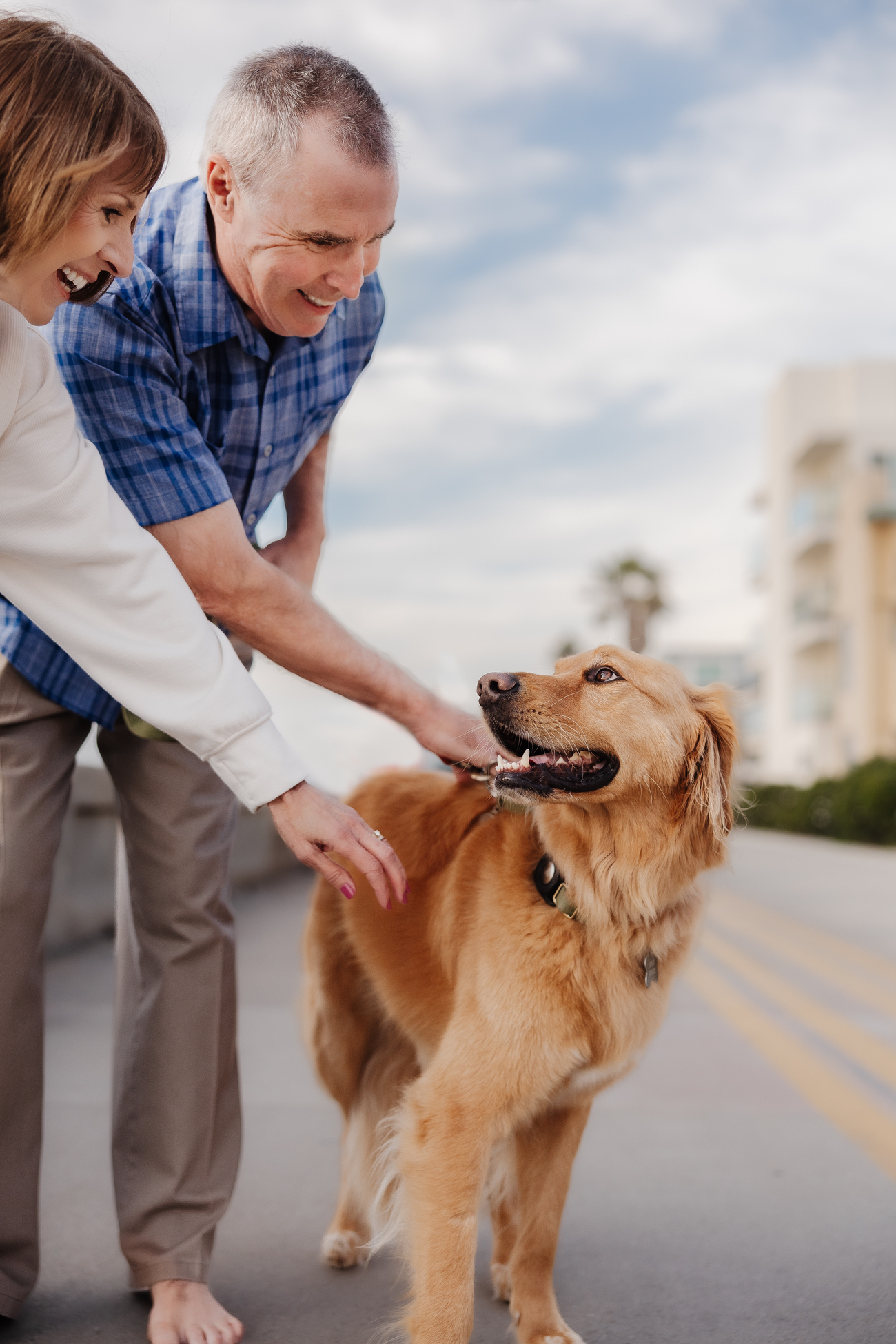 Couple comforting a golden retriever outdoors