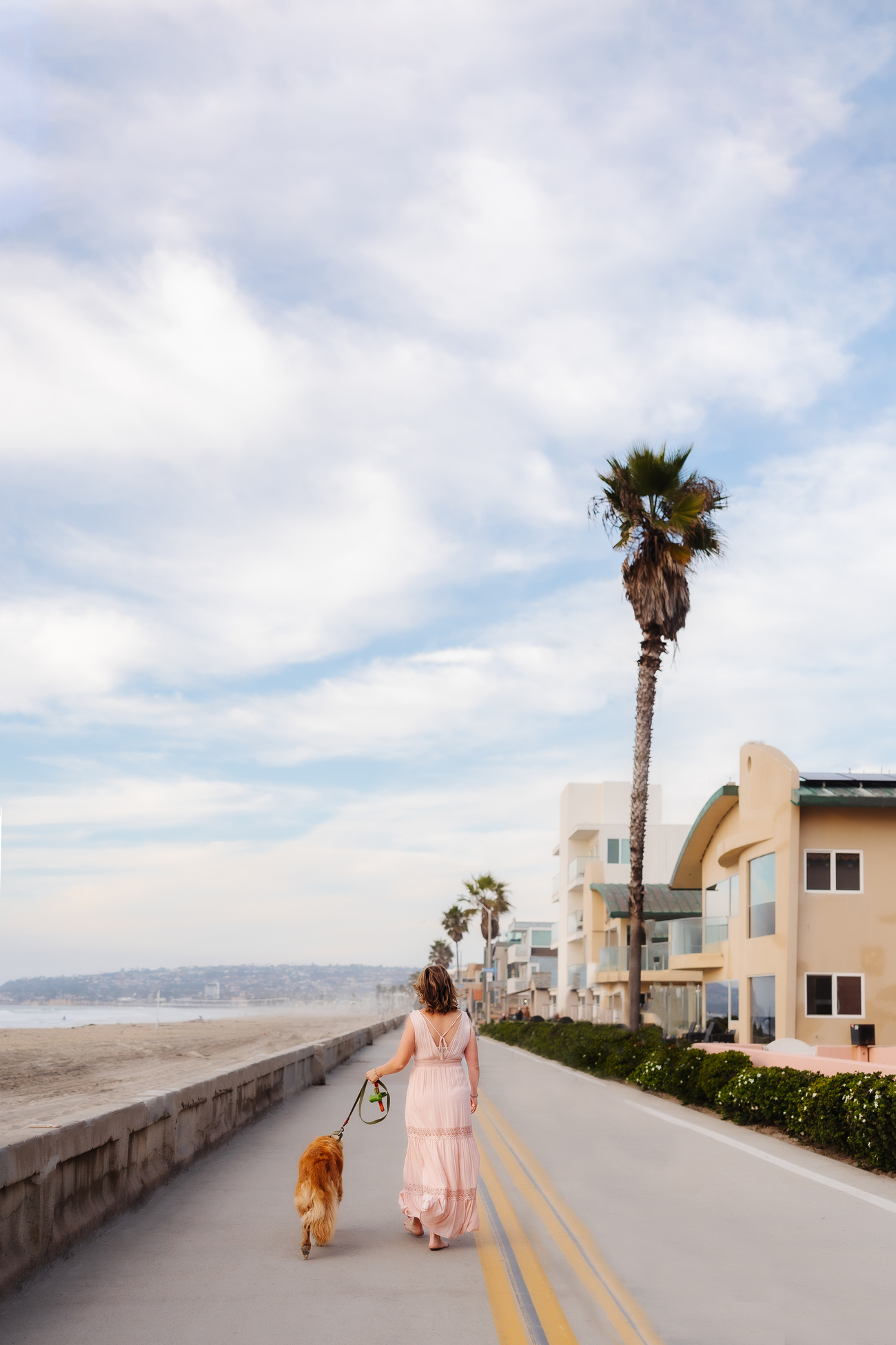 Woman walking dog along beachfront path