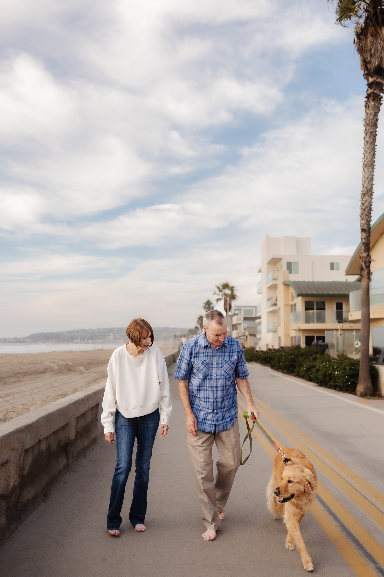 Couple walking golden retriever by the beach