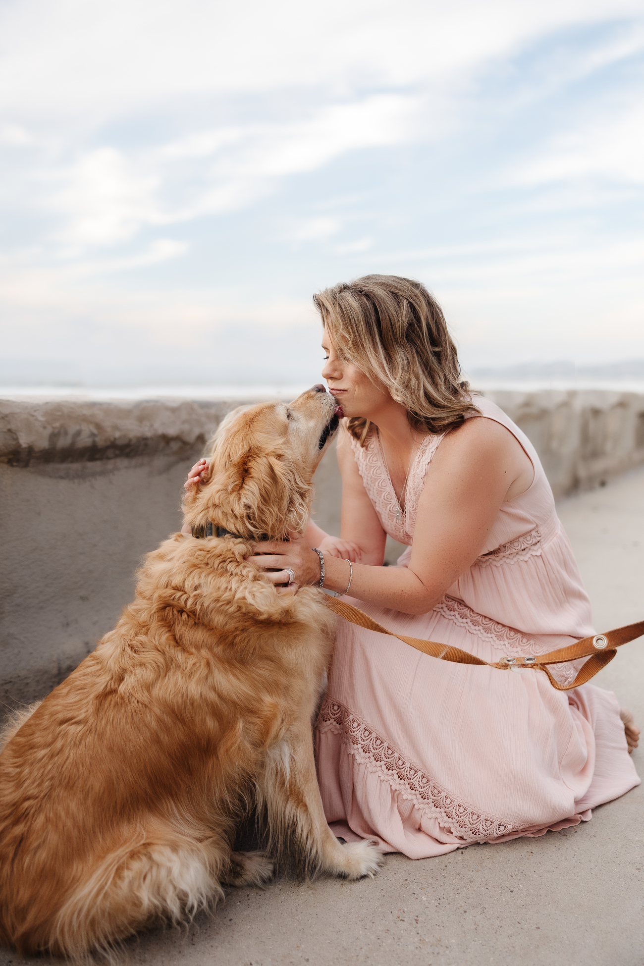 Woman kissing golden retriever on the beach