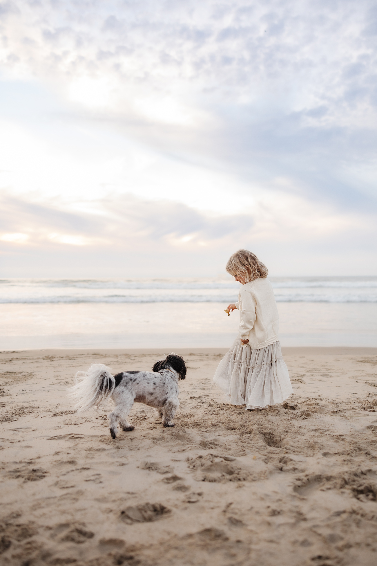 Child with small dog on sandy beach