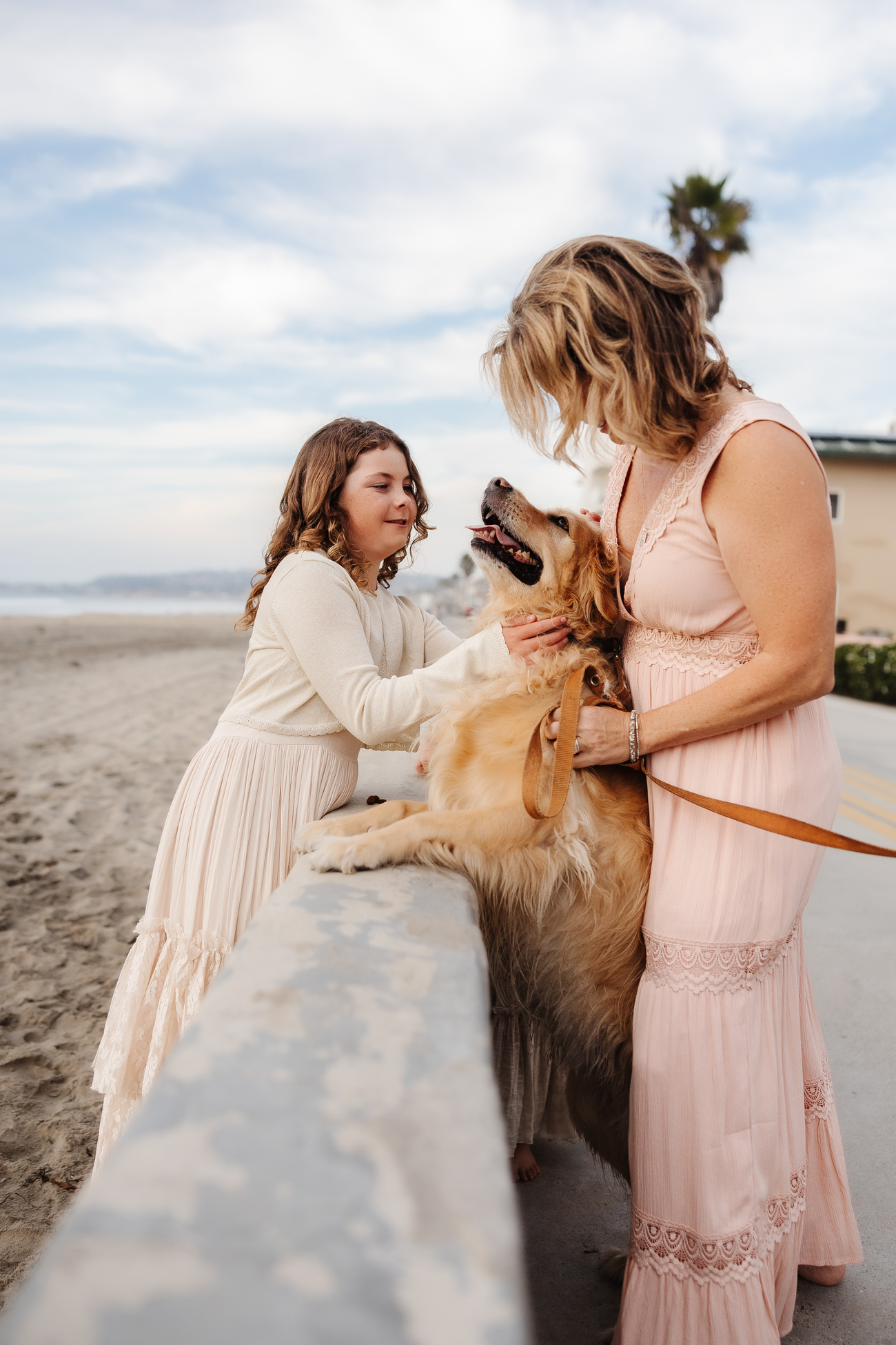 Woman and child petting a golden retriever at the beach